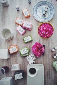 overhead image of colorful soaps, serums, flowers and coffee cups