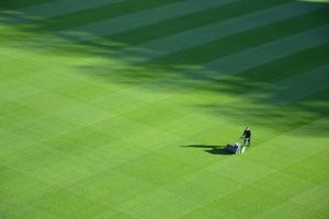 person hand mowing a stadium sized lawn