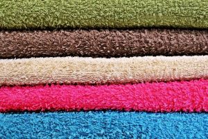 stack of folded towels in green, brown, beige, pink and blue