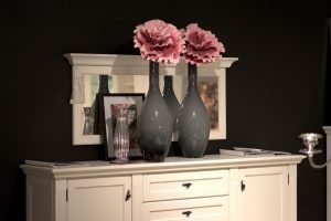 cream colored dresser with two large grey vases with a big pink flower in each vase