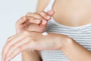 lady applying white hand lotion on the back of her hand