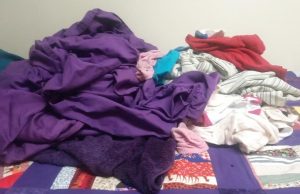 pile of unfolded, rumpled clothes on a bed
