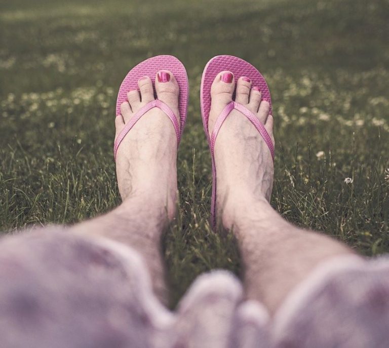 hairy legs wearing flip flops and pink nail polish